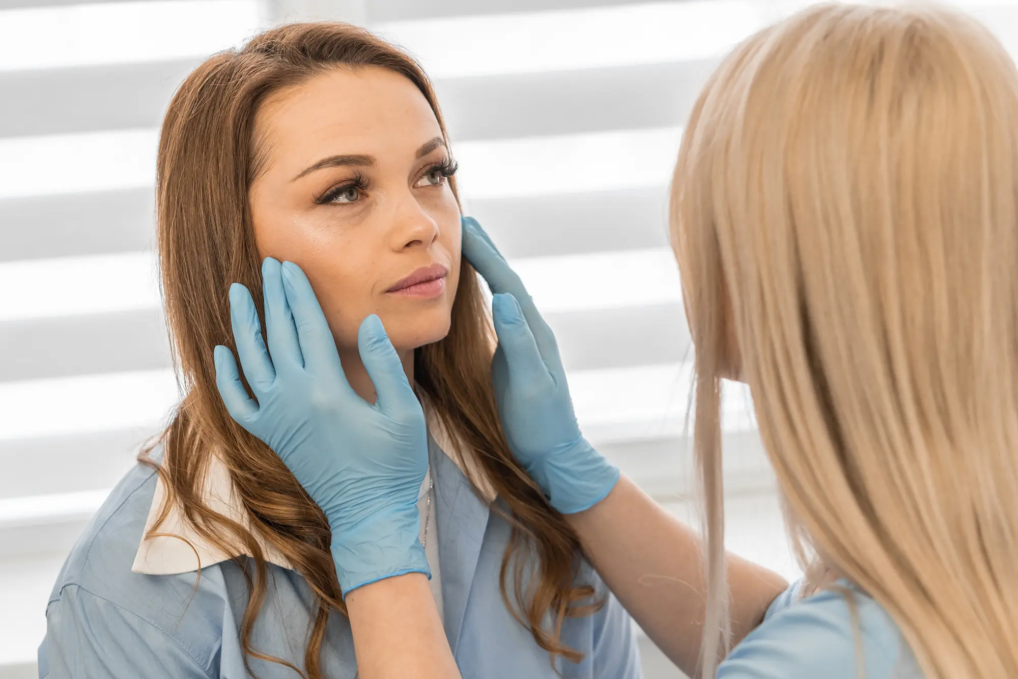 nurse with blue gloves examining womans face