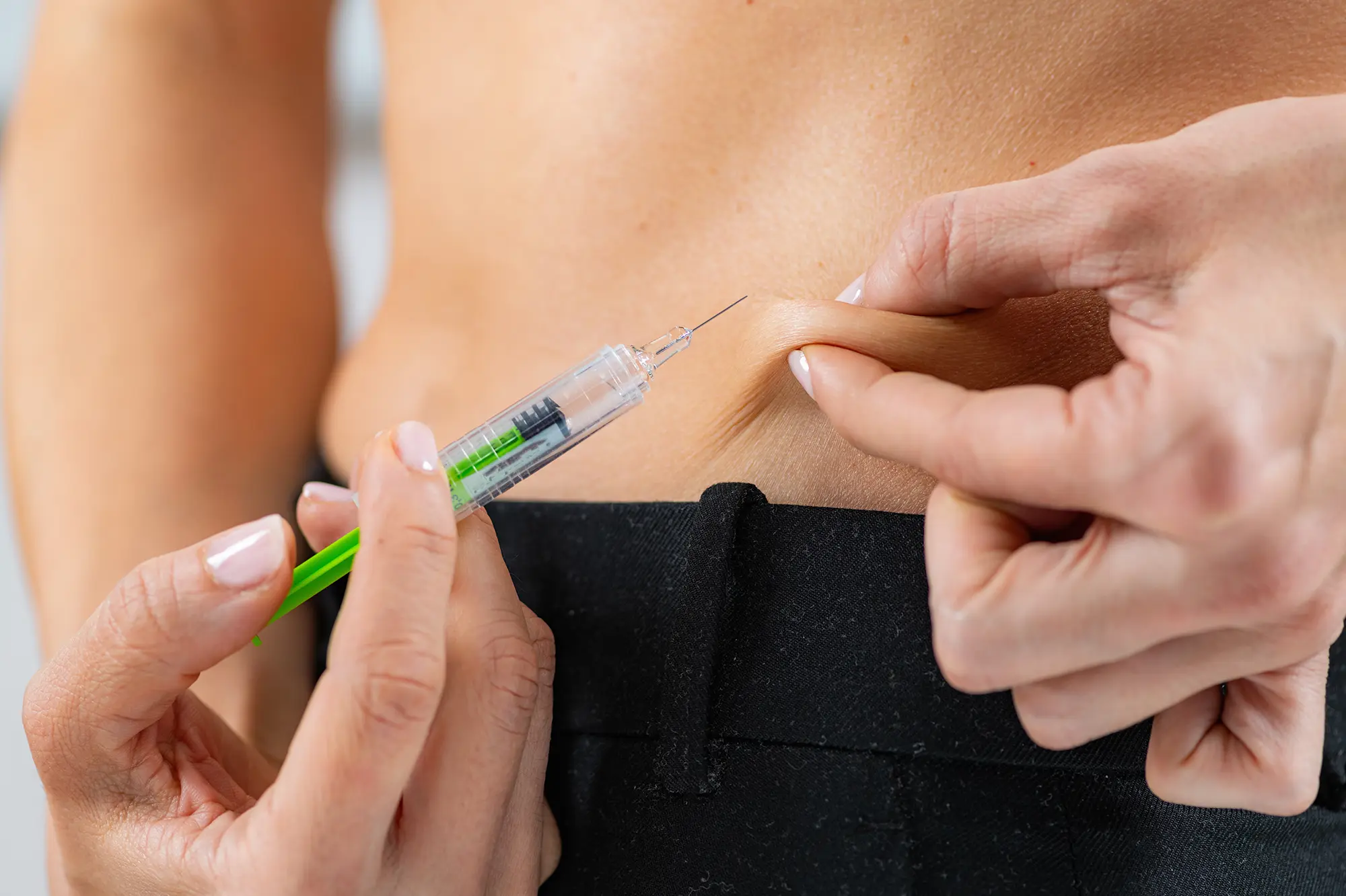 up close image of person giving themselves a shot in the stomach